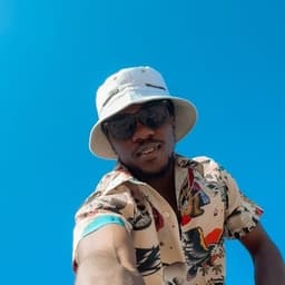 Anuoluwapo in a white bucket hat and sunglasses against a blue sky
